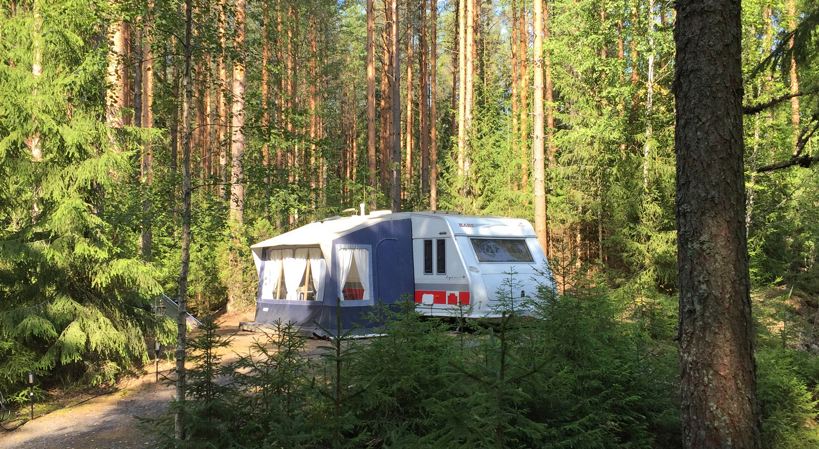 Matkailuvaunu etuteltalla havumetsän siimeksessä vaunualueella.