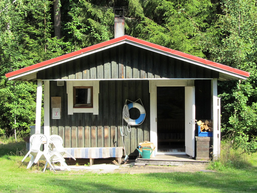 Pieni saunarakennus lammen rannalla.
