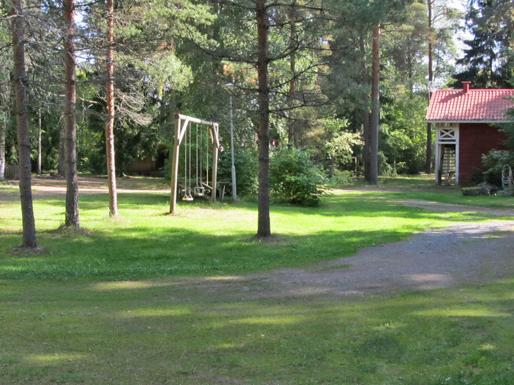 Leirintäalueen huoltorakennus ja keinu.